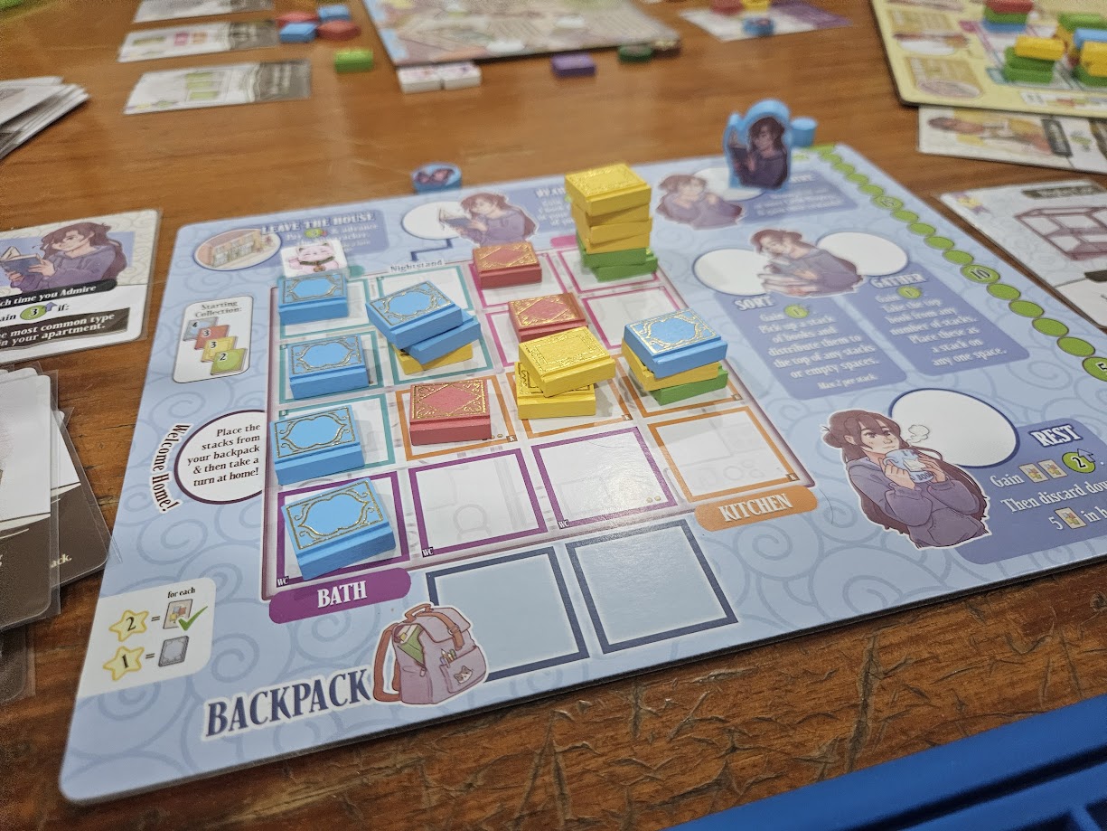 Gameplay photo of the board game A Place for All My Books featuring various components and board state.