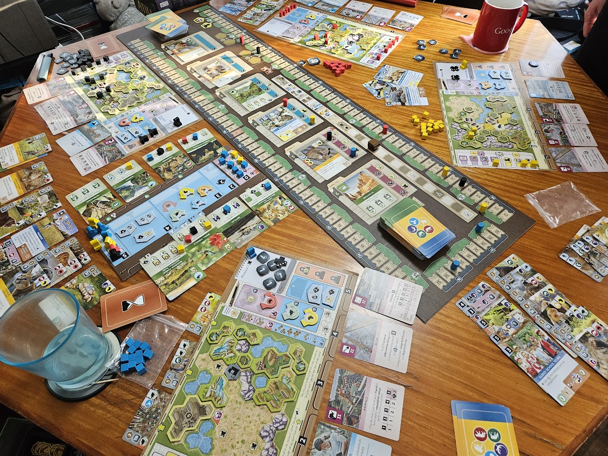 Gameplay photo of the board game Ark Nova featuring various components and board state.