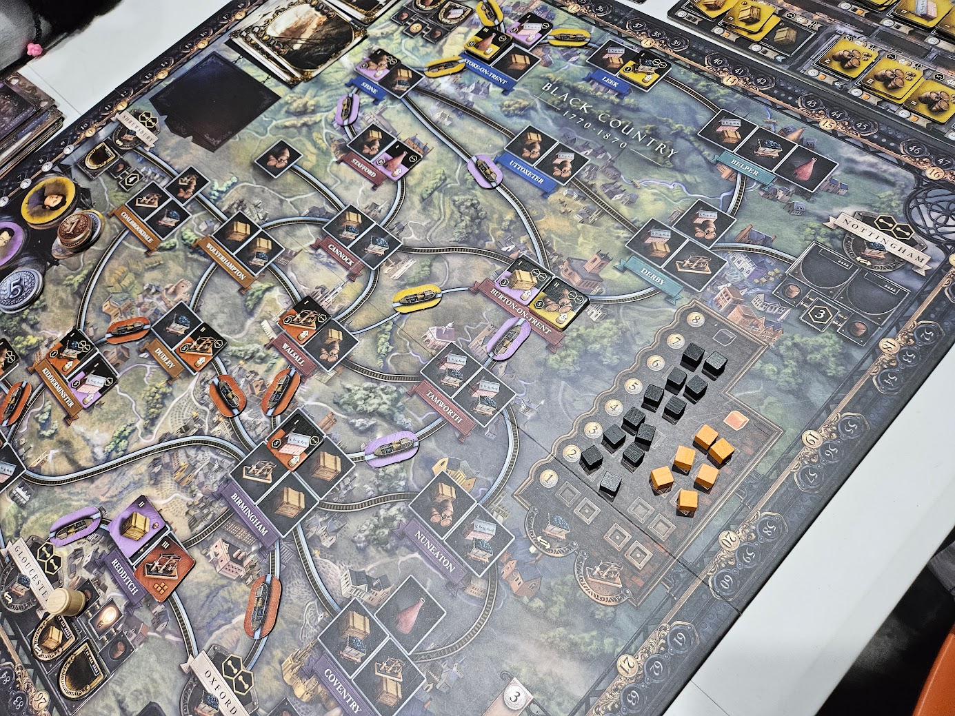 Gameplay photo of the board game Brass: Birmingham featuring various components and board state.