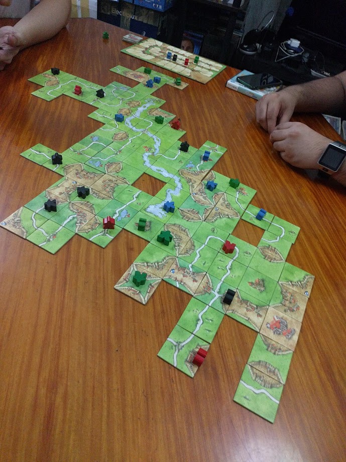 Gameplay photo of the board game Carcassonne featuring various components and board state.