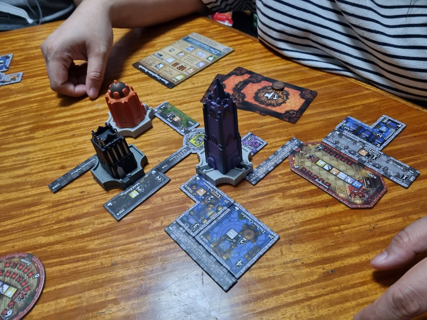 Gameplay photo of the board game Castles of Mad King Ludwig: Royal Collector's Edition featuring various components and board state.