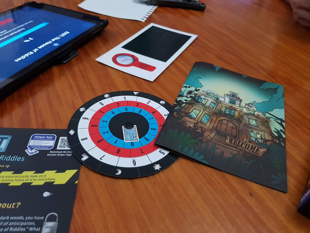 Gameplay photo of the board game EXIT: The Game – The House of Riddles featuring various components and board state.