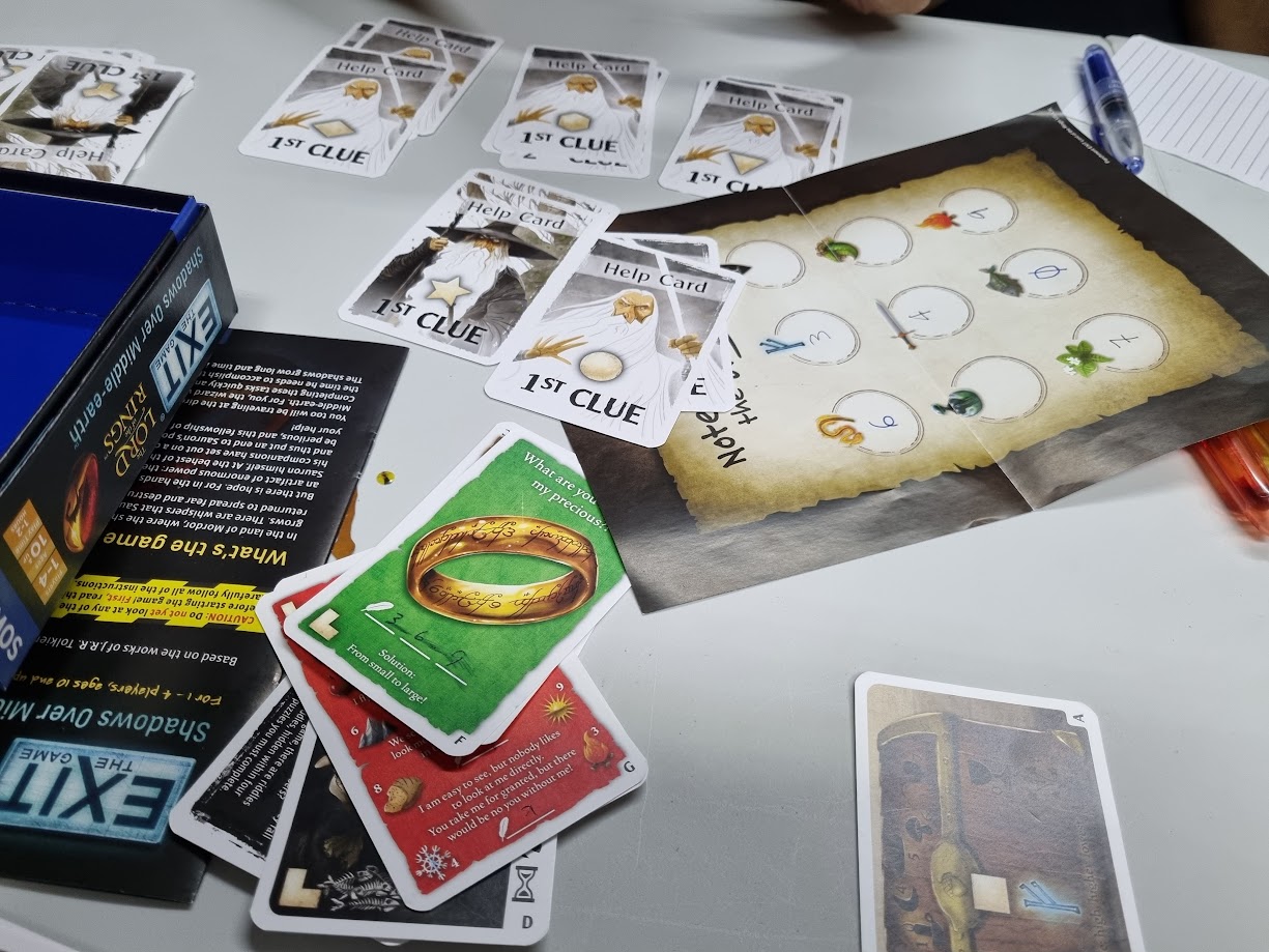 Gameplay photo of the board game EXIT: The Game – The Lord of the Rings: Shadows over Middle-earth featuring various components and board state.