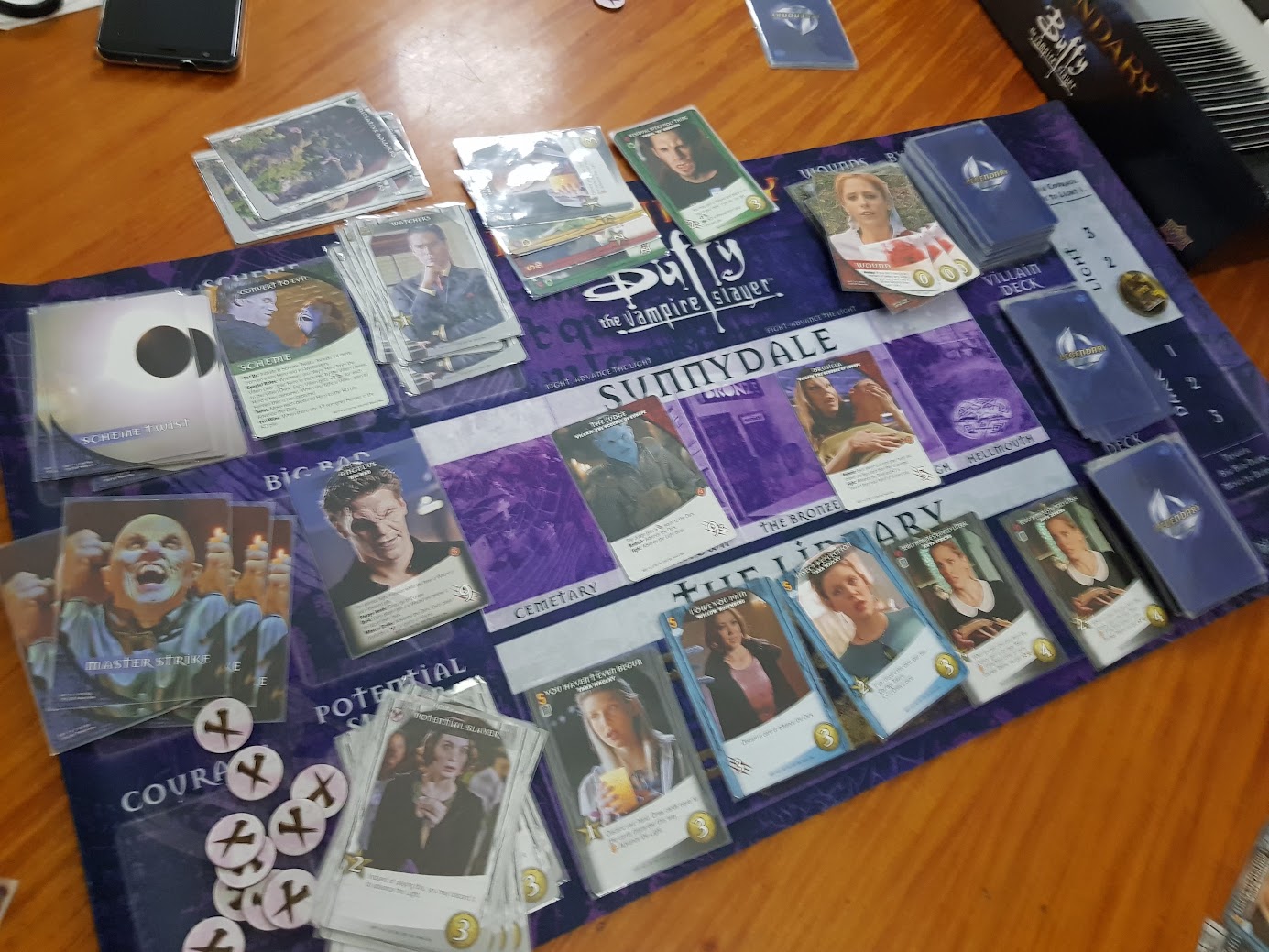 Gameplay photo of the board game Legendary: Buffy The Vampire Slayer featuring various components and board state.