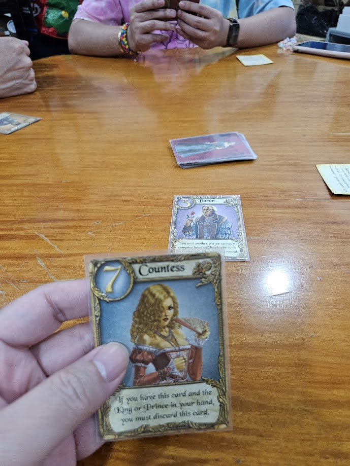 Gameplay photo of the board game Love Letter featuring various components and board state.