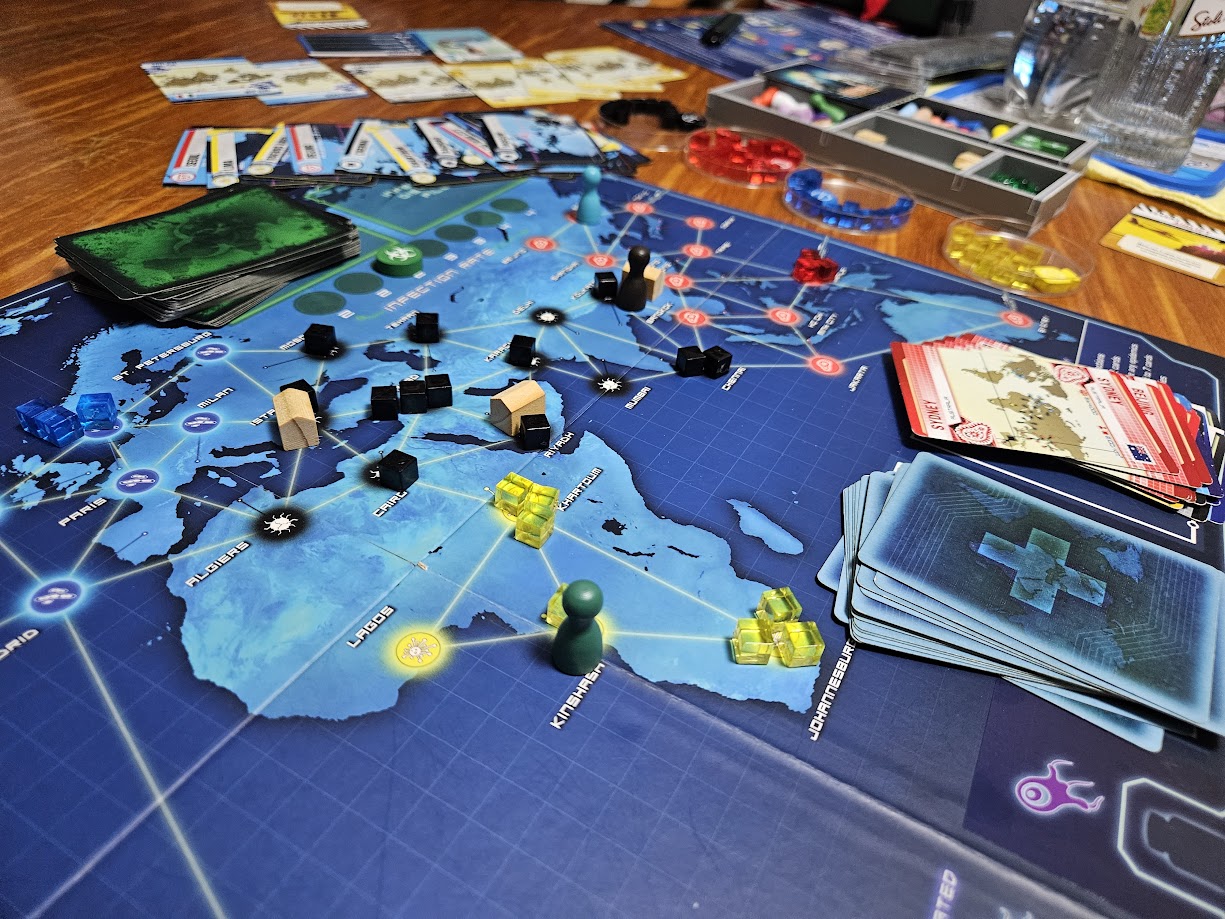 Gameplay photo of the board game Pandemic featuring various components and board state.