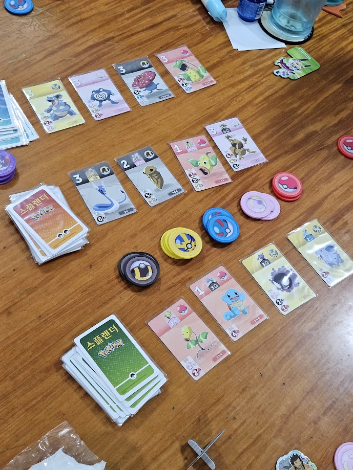 Gameplay photo of the board game 스플렌더: Pokémon (Splendor: Pokémon) featuring various components and board state.