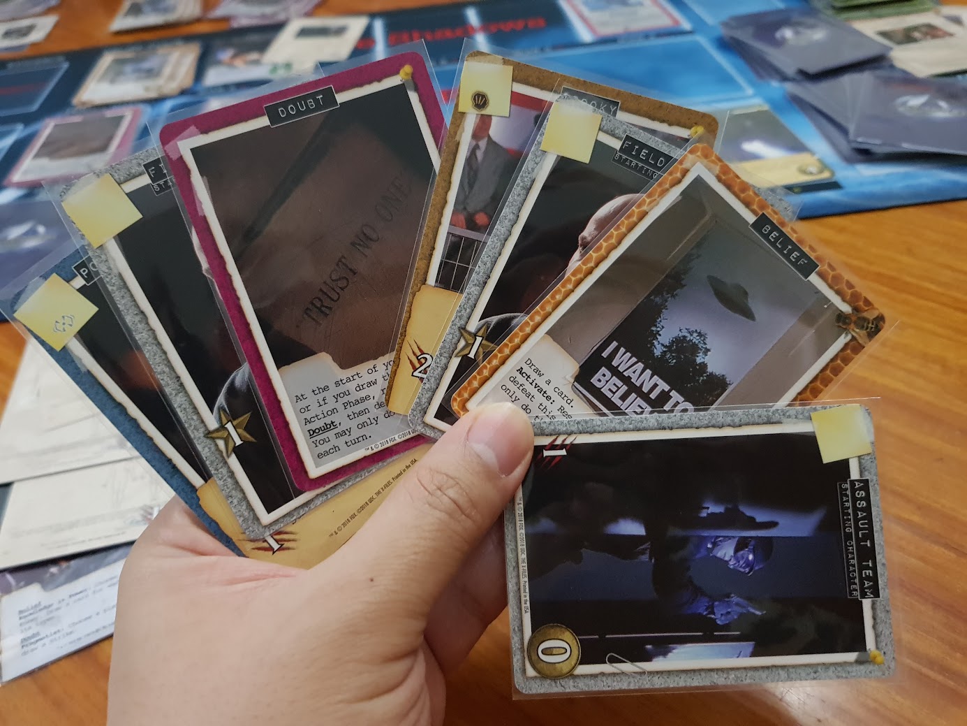 Gameplay photo of the board game Legendary Encounters: The X-Files Deck Building Game featuring various components and board state.