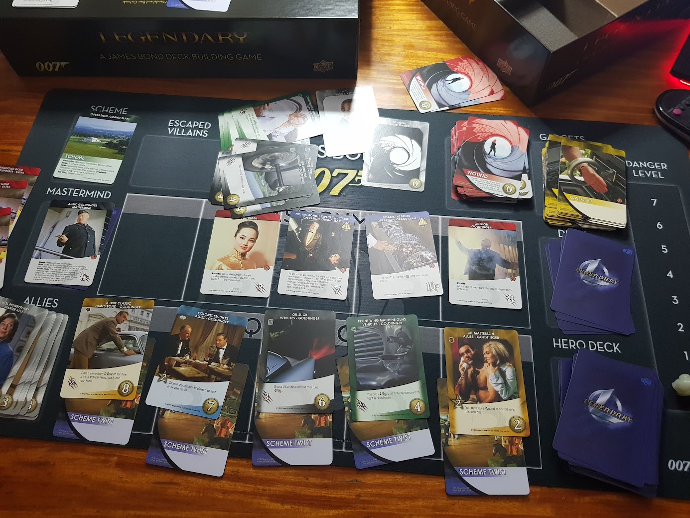 Gameplay photo of the board game Legendary: A James Bond Deck Building Game featuring various components and board state.