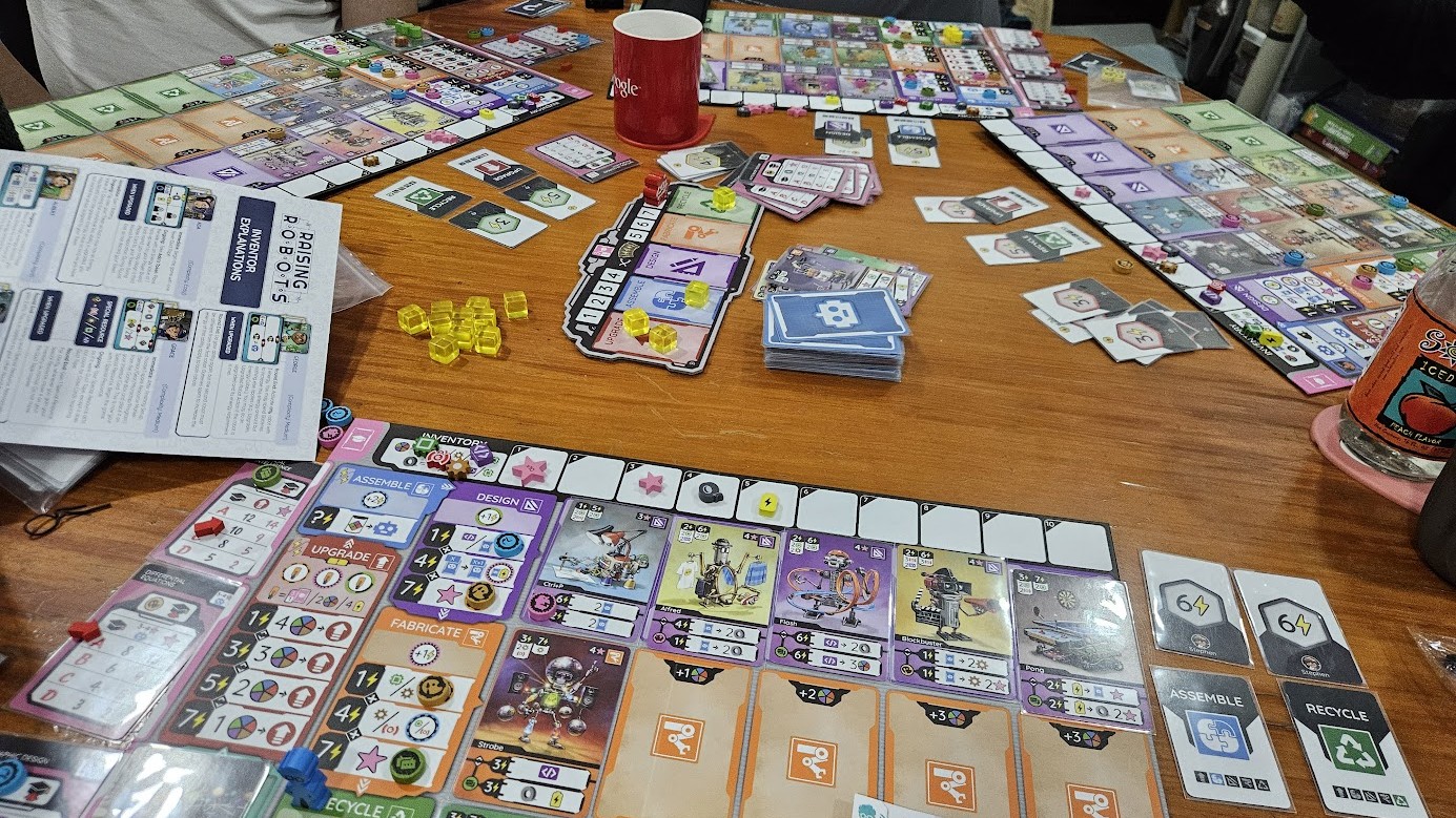 Gameplay photo of the board game Raising Robots: Deluxe featuring various components and board state.