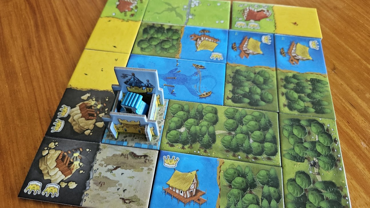 Gameplay photo of the board game Kingdomino featuring various components and board state.