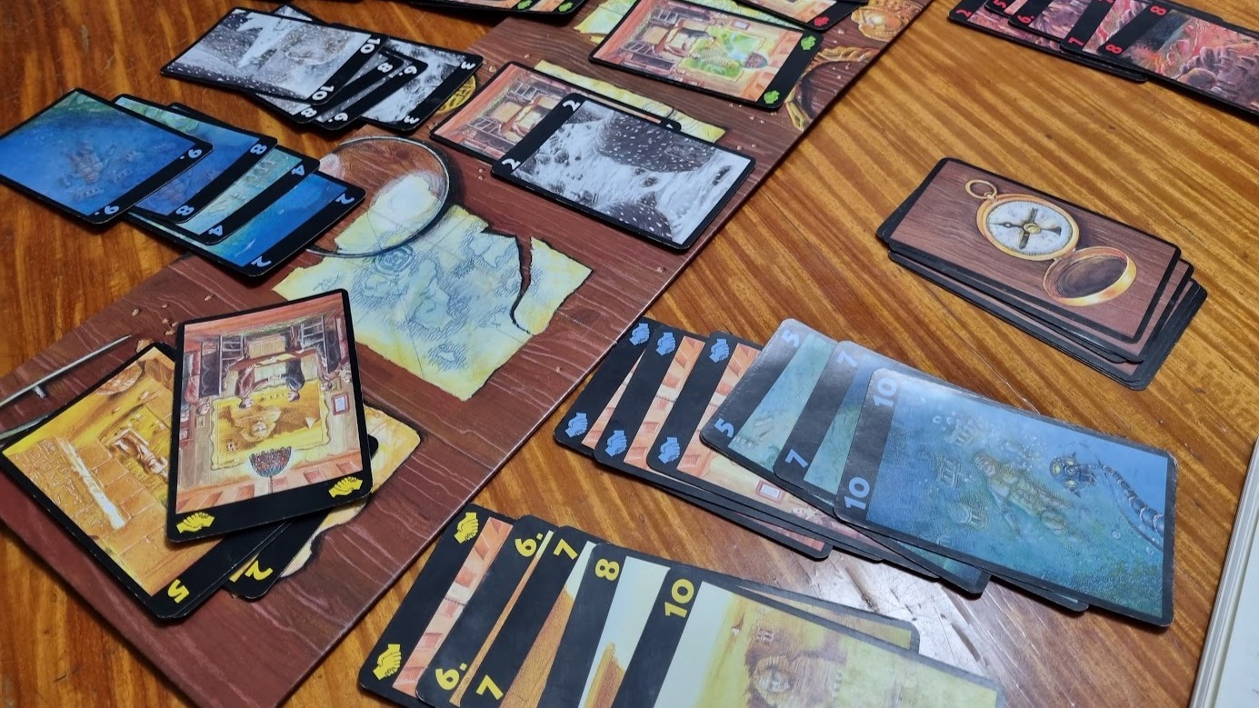 Gameplay photo of the board game Lost Cities featuring various components and board state.