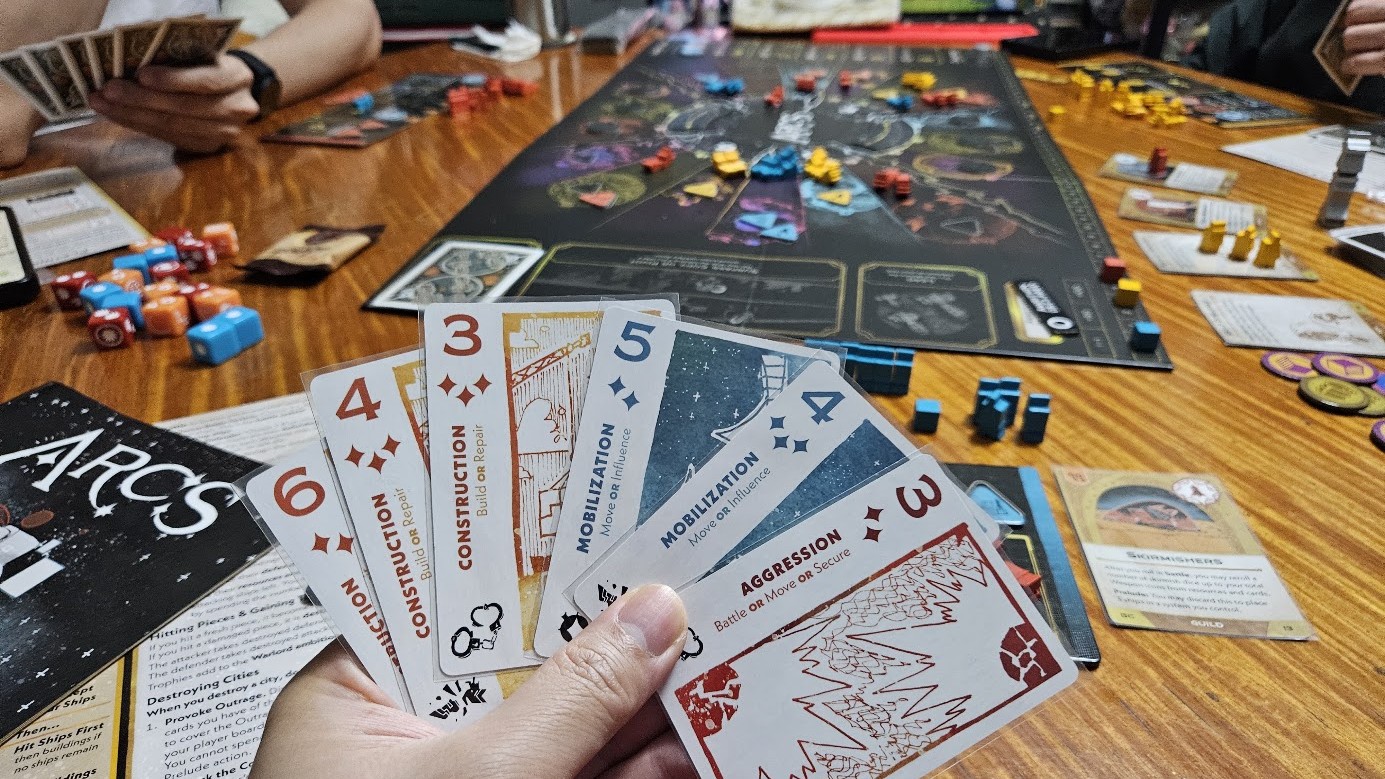 Gameplay photo of the board game Arcs featuring various components and board state.
