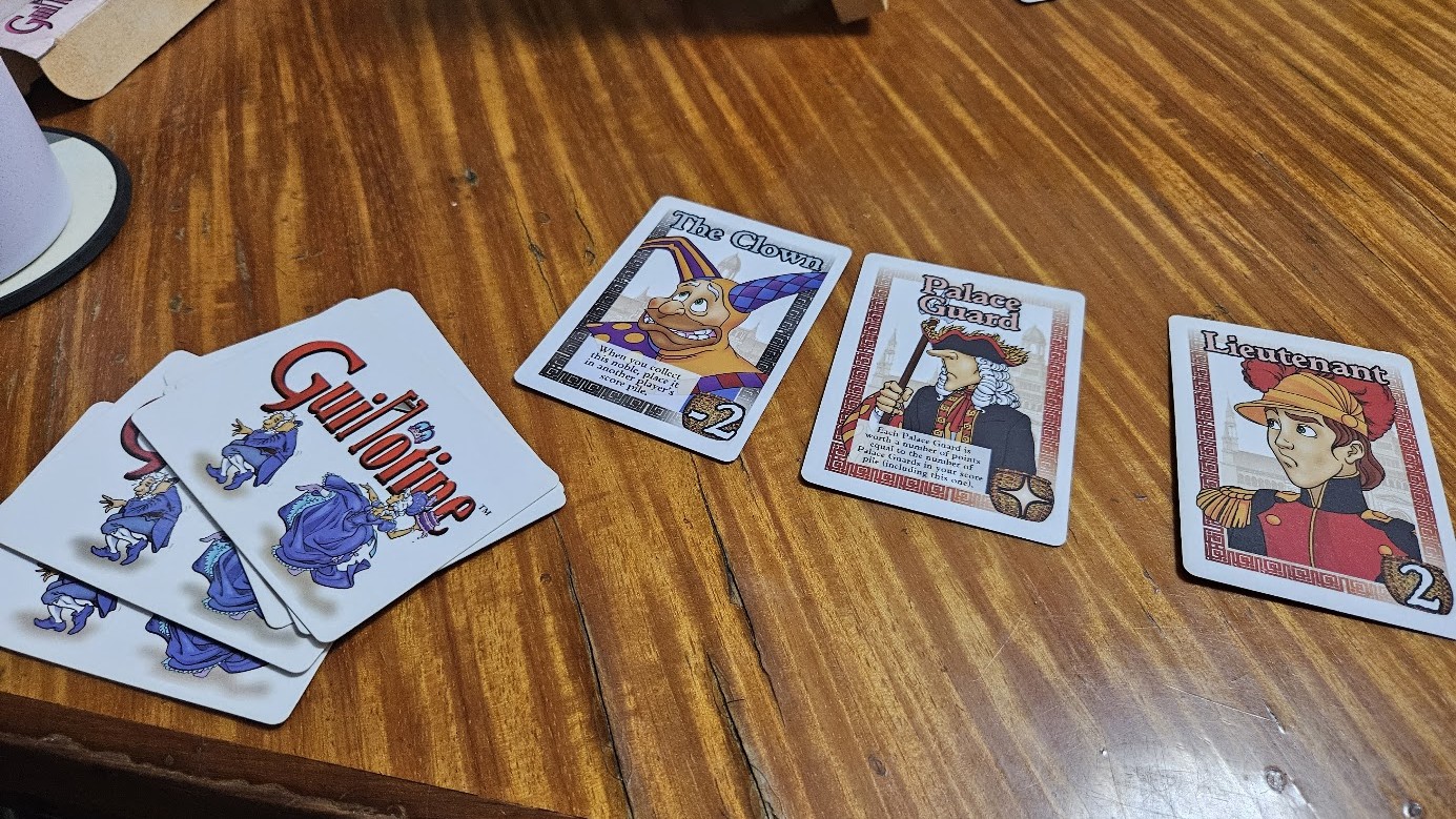 Gameplay photo of the board game Guillotine featuring various components and board state.