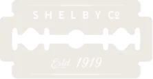 A black razor blade with four holes in the middle against a light background.