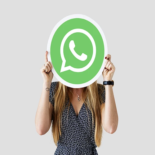 Woman holding WhatsApp logo sign in front of her face representing messaging and digital communication