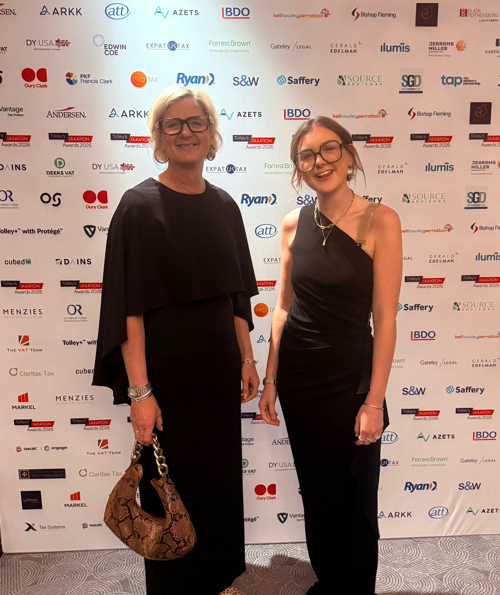 Two women posing at the Tolley’s Taxation Awards 2026 event in front of a branded sponsor backdrop.
