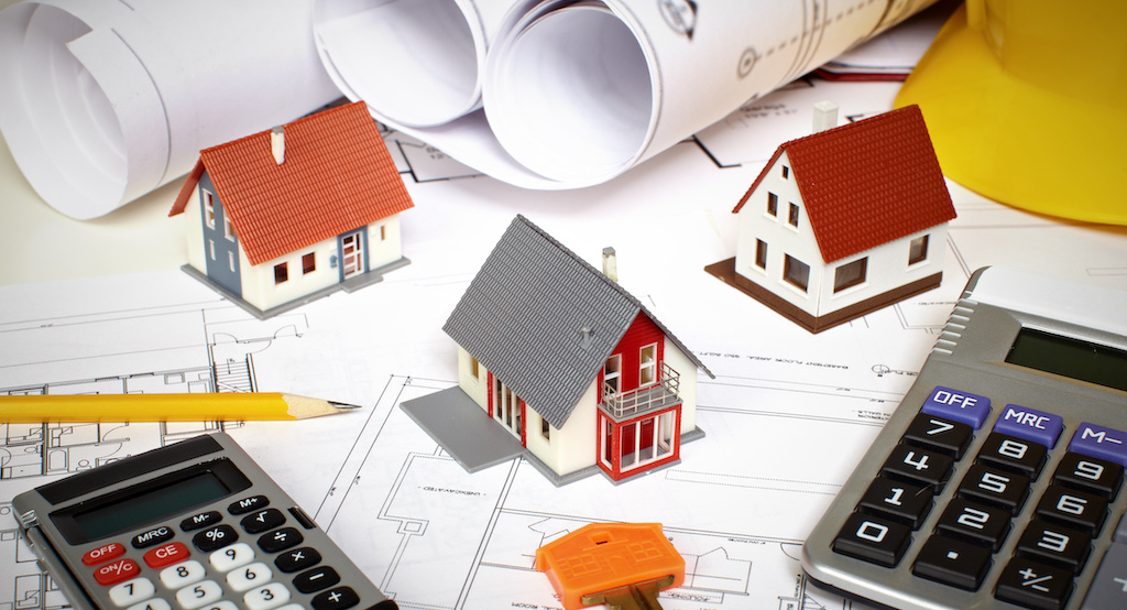 Property models, calculators and architectural plans arranged on a desk, symbolising SDLT calculations, property purchases, additional dwelling surcharges, residential property tax planning and complex conveyancing transactions.