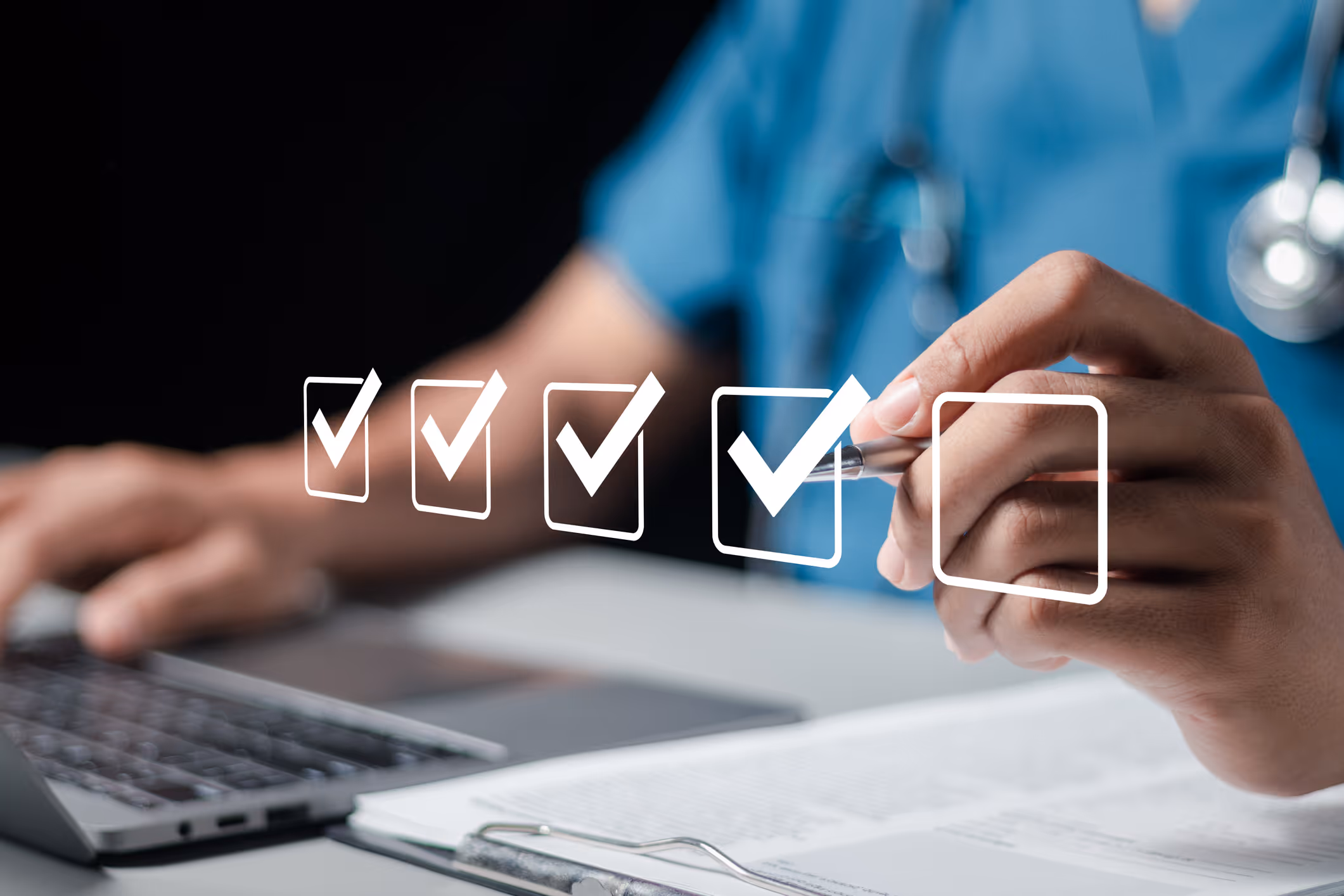 Hand holding pen marking the fourth of five checkboxes in front of a doctor using a laptop.