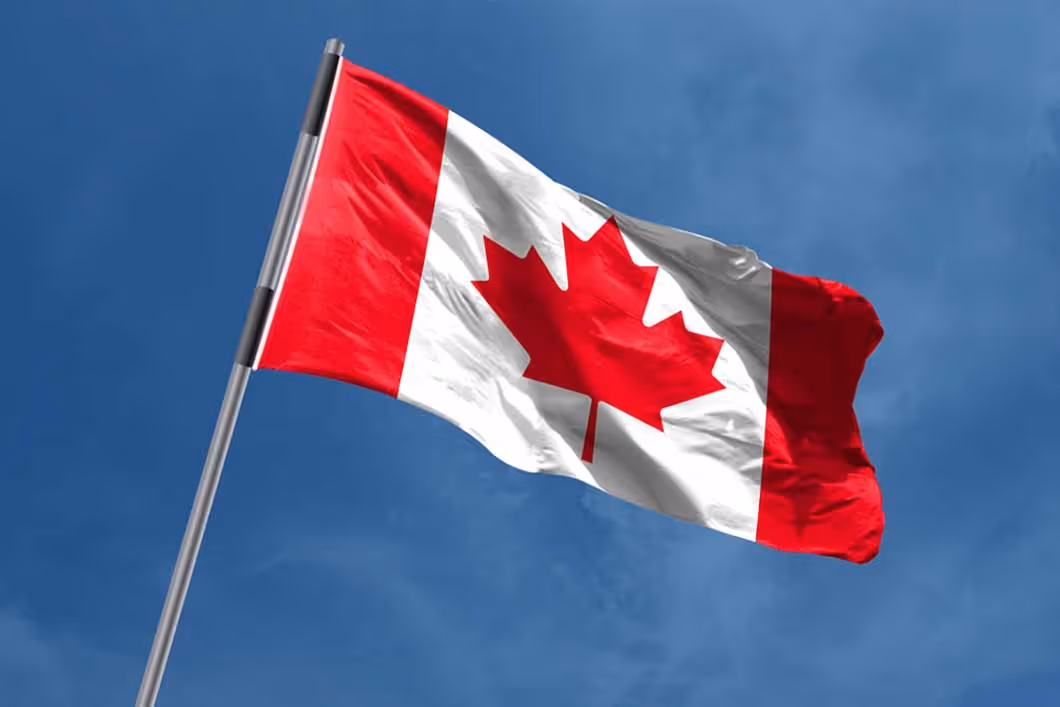 Canadian flag flying in the wind on a pole.