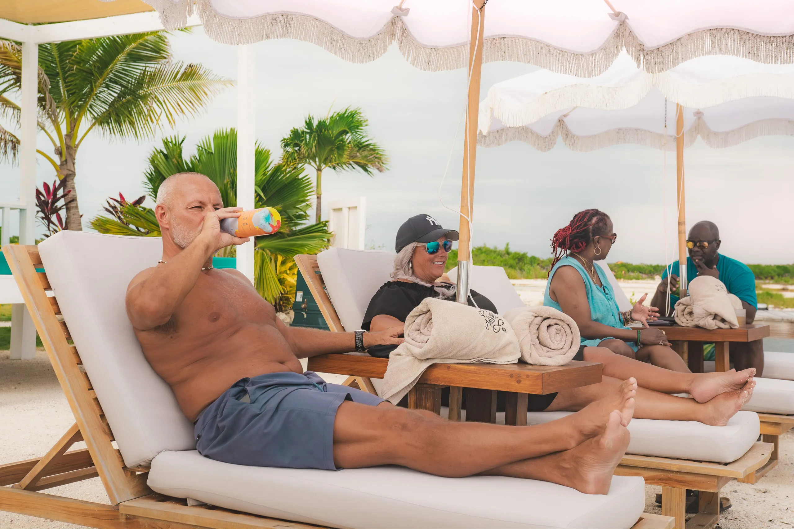 Guests relaxing on beach loungers under umbrellas.