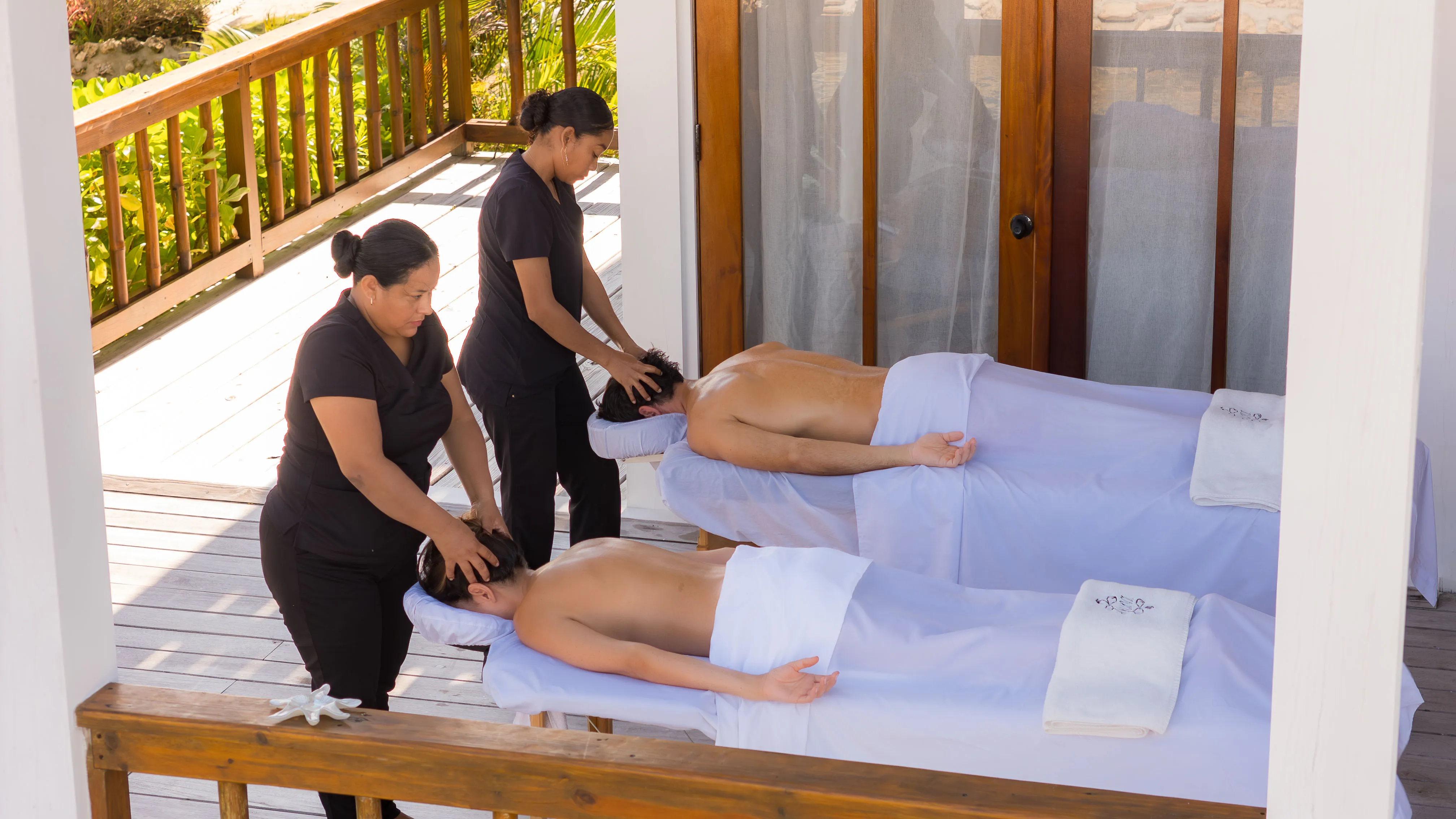Couples massage on outdoor spa deck at Aruna Resort Ambergris Caye