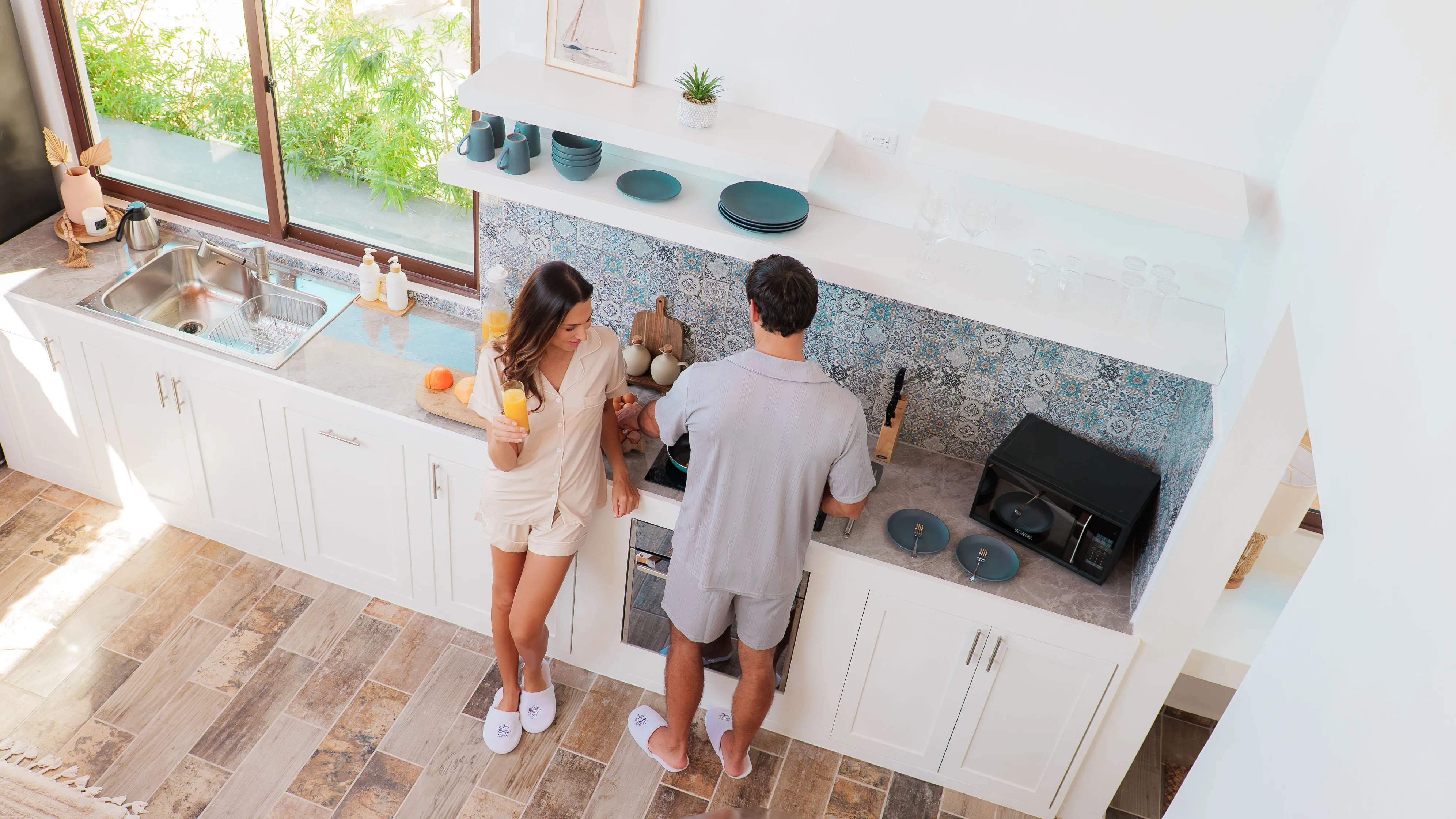 Guest enjoying fresh orange juice while partner cooks breakfast