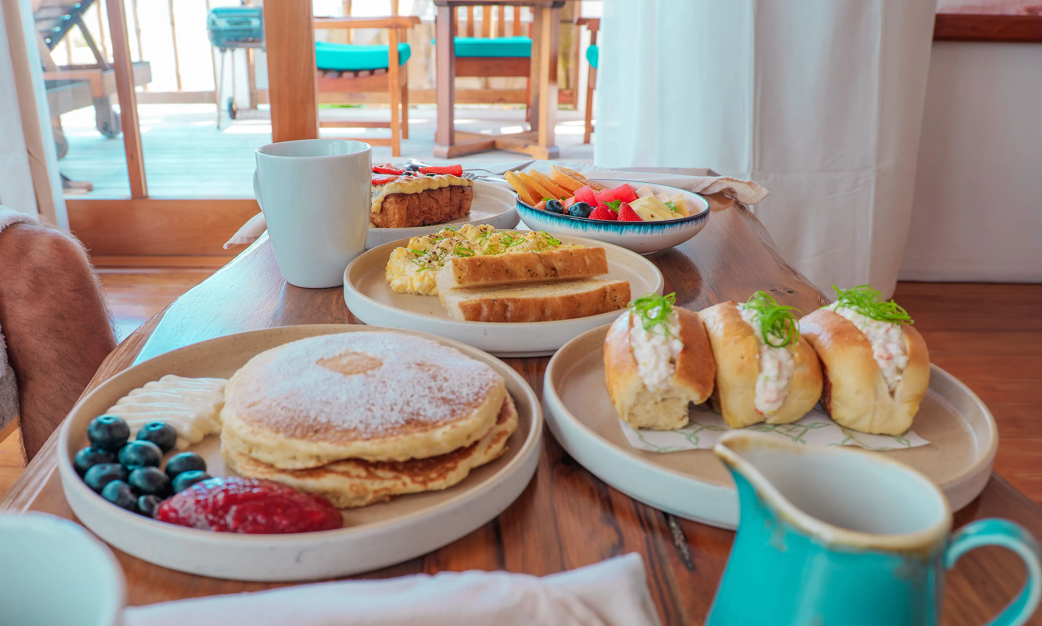 Breakfast spread with pancakes, fruit, eggs, and pastries at Aruna Resort villa terrace
