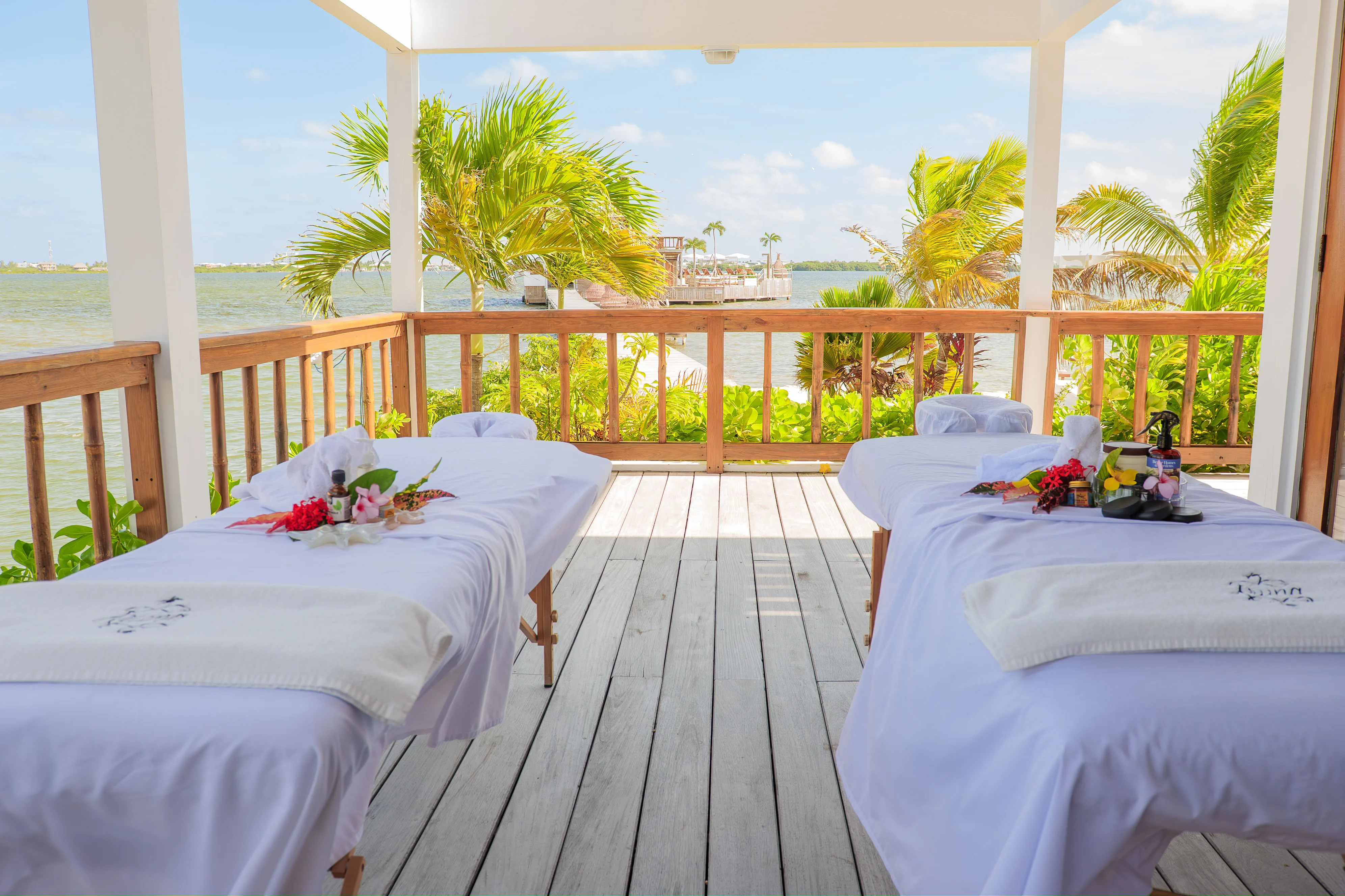 Outdoor spa massage beds overlooking the water and palm trees
