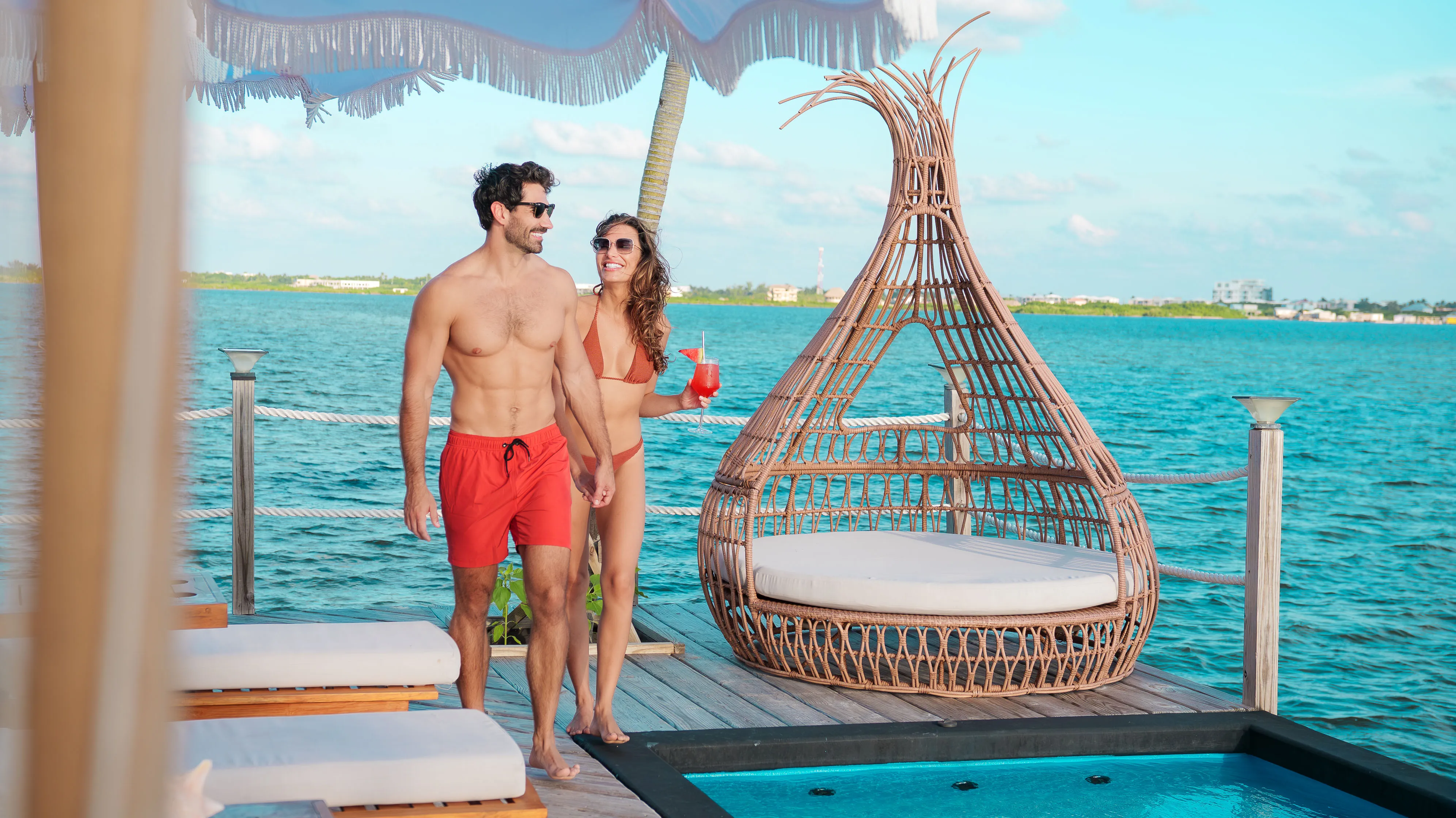 Couple walking together by the infinity pool and waterfront lounge area