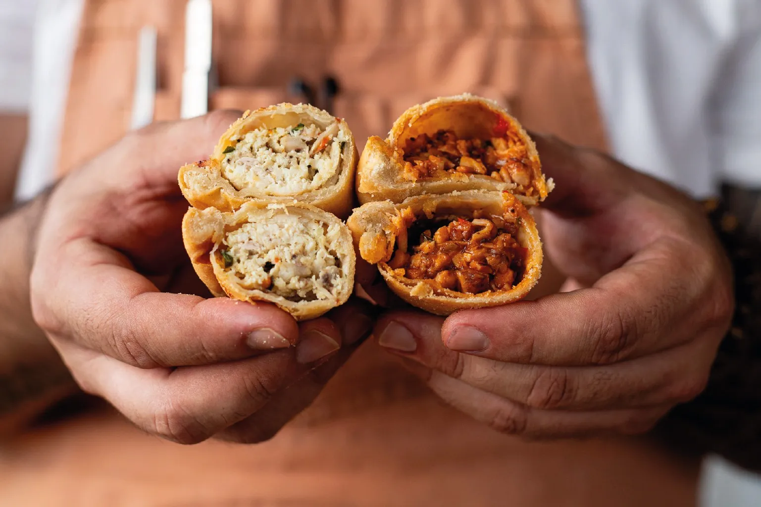 Hands holding freshly cut empanadas with savory fillings