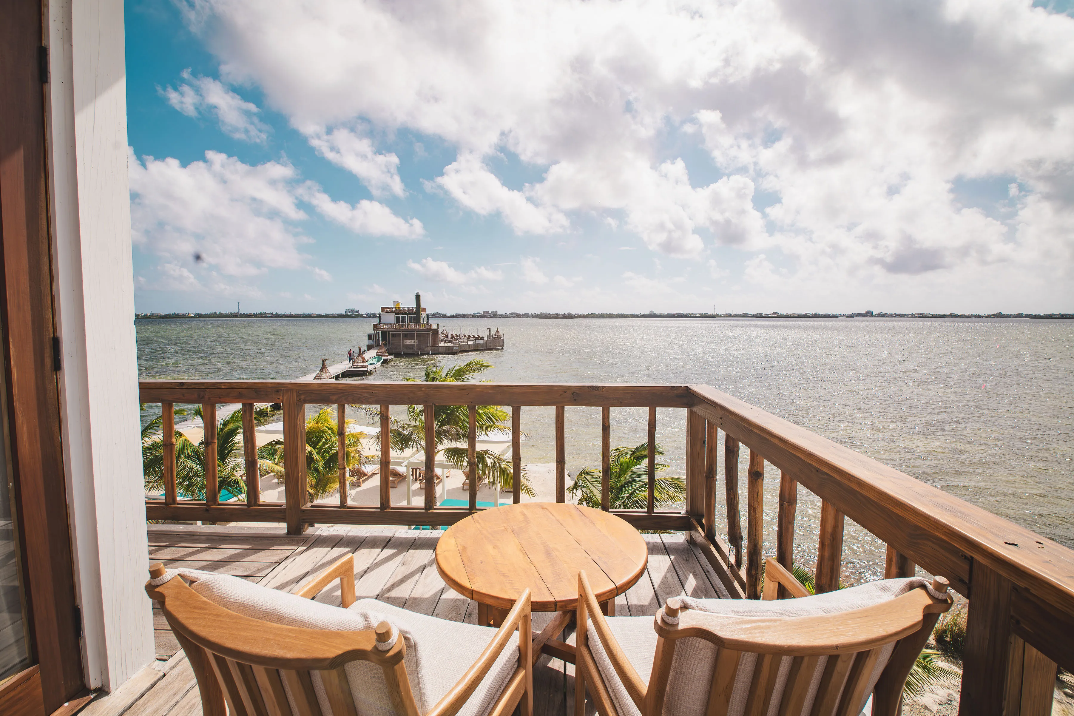 Private balcony with seating overlooking the ocean and a dock extending into the water
