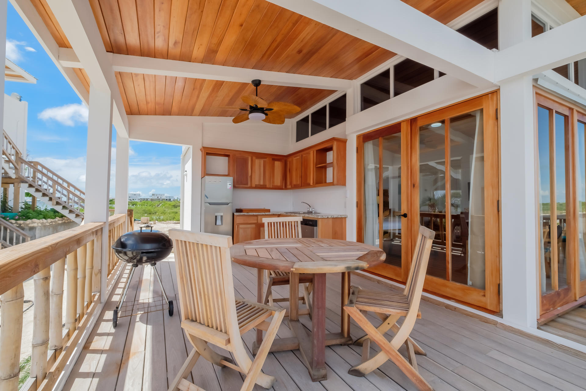 Open-air patio with round dining table and chairs overlooking lush mangroves and coastal scenery.
