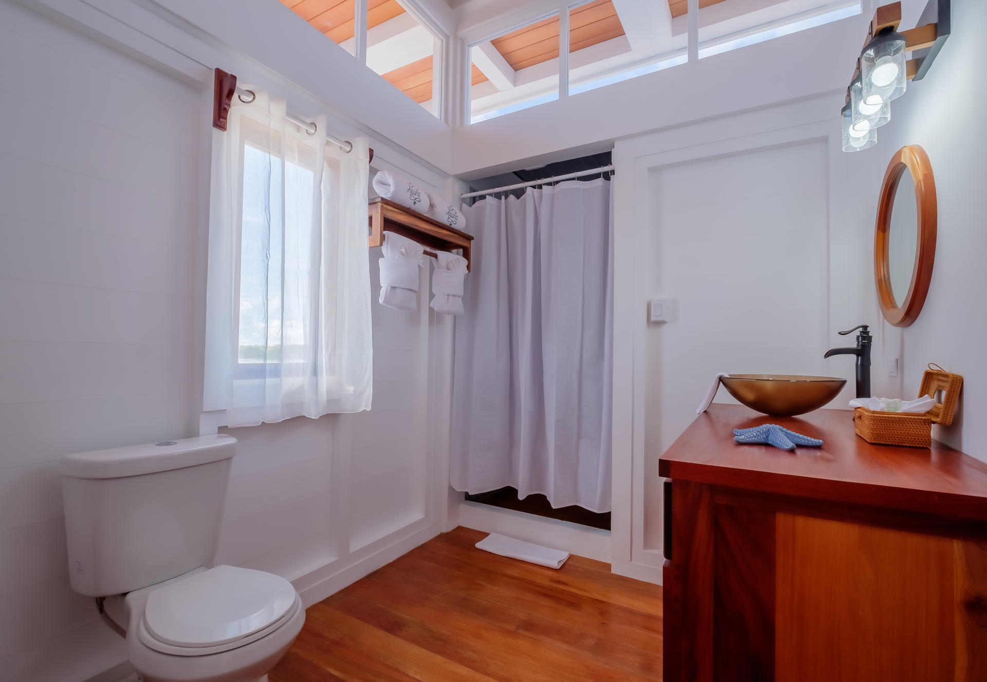 Comfortable armchair beside sliding glass doors leading to a sunlit balcony with tropical plants.
