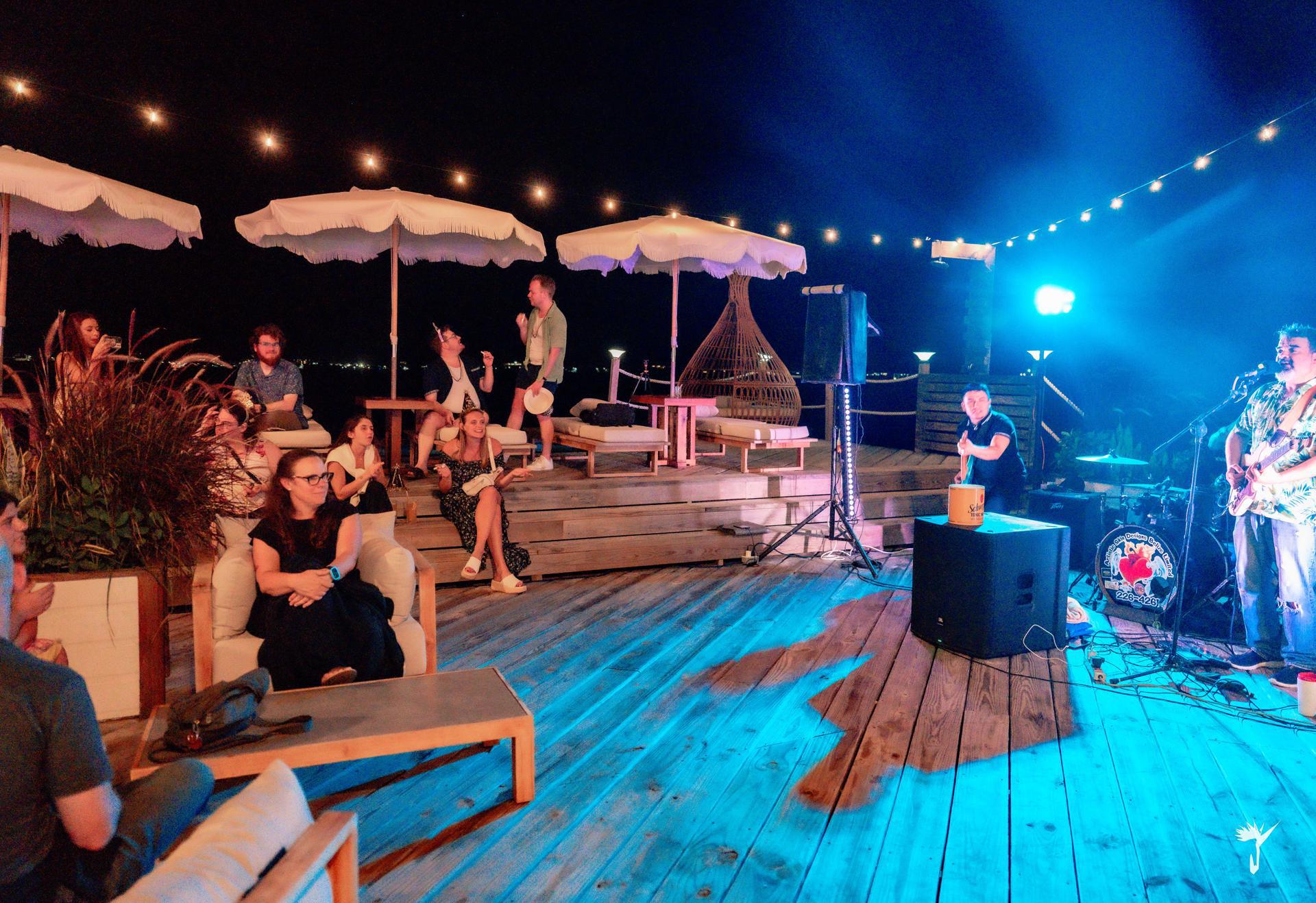 Guests enjoying live music under string lights on the Aruna deck
