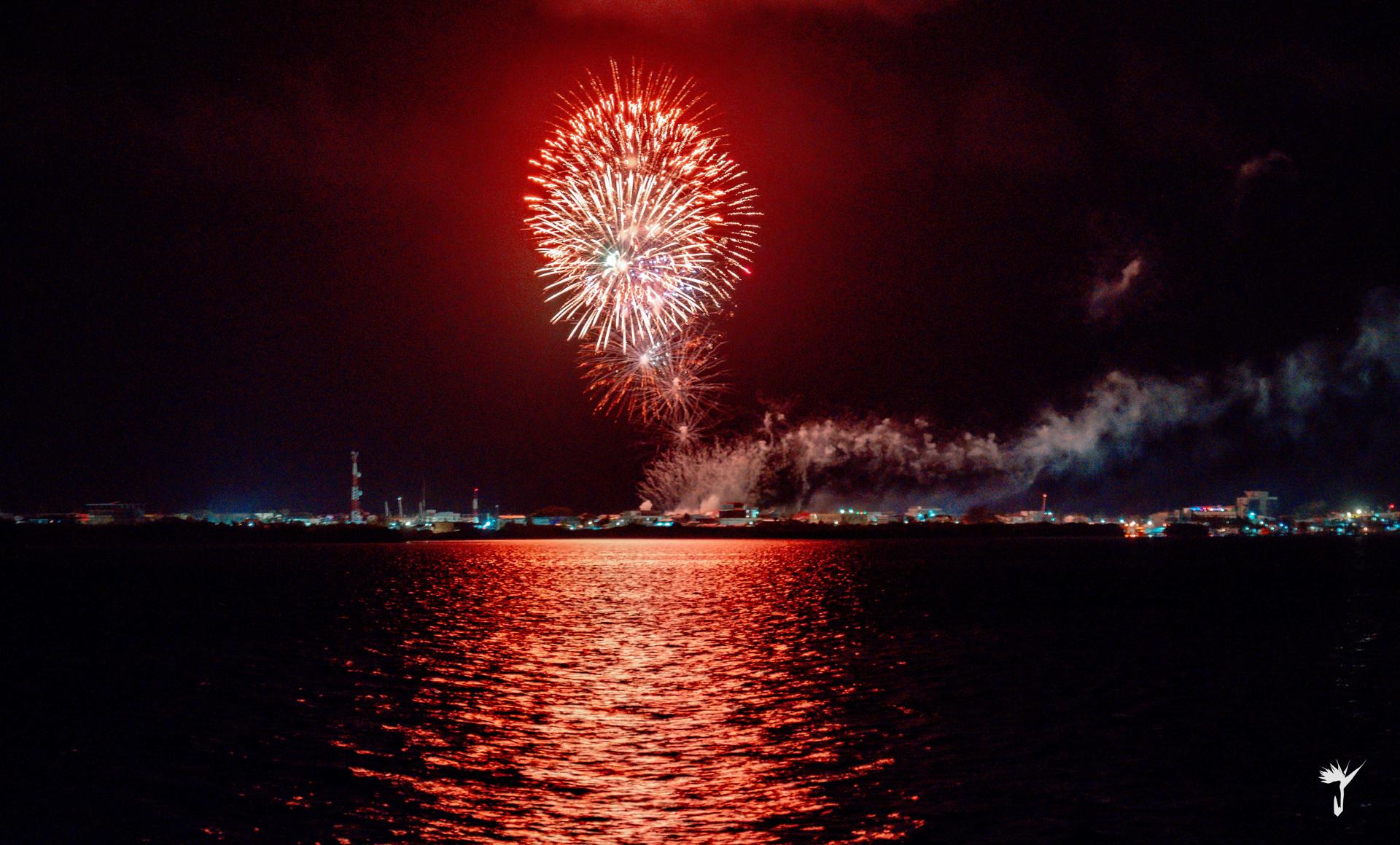 Red fireworks bursting over the water in Placencia, Belize