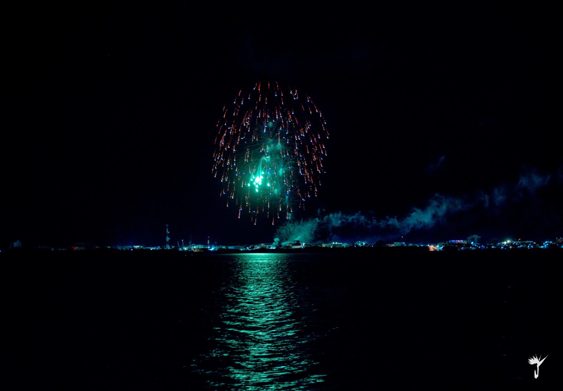 Green and blue fireworks reflected on the sea near Aruna Resort