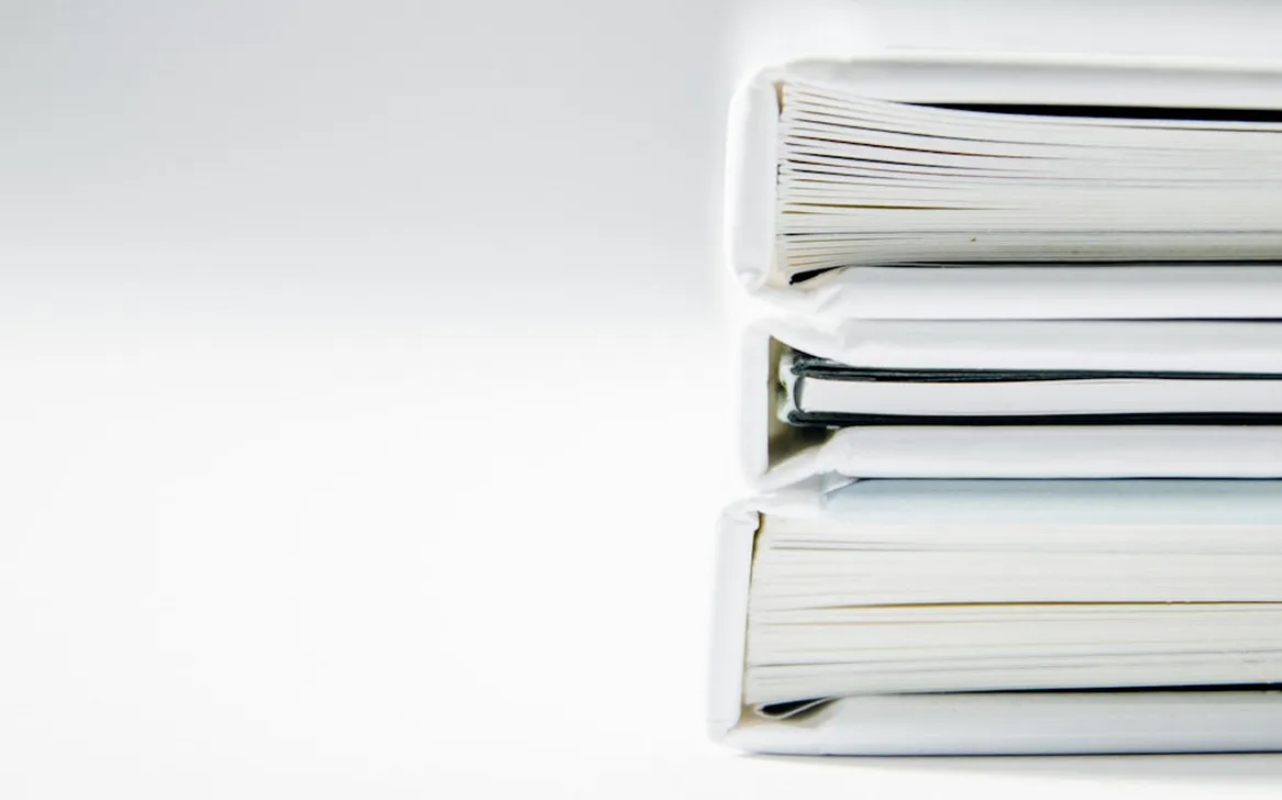 Stack of three closed white hardcover books viewed from their spines on a white background.