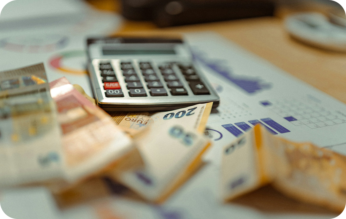 Calculator and scattered Euro banknotes on a financial report with charts and graphs.