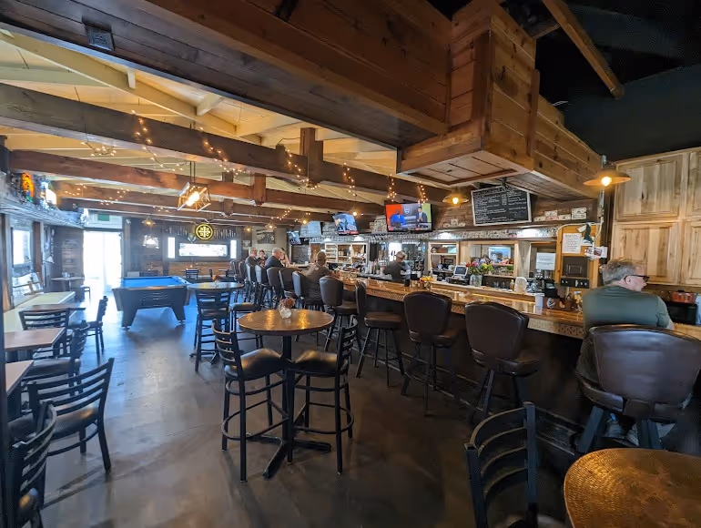 A bar with a wooden ceiling and a blue pool table.
