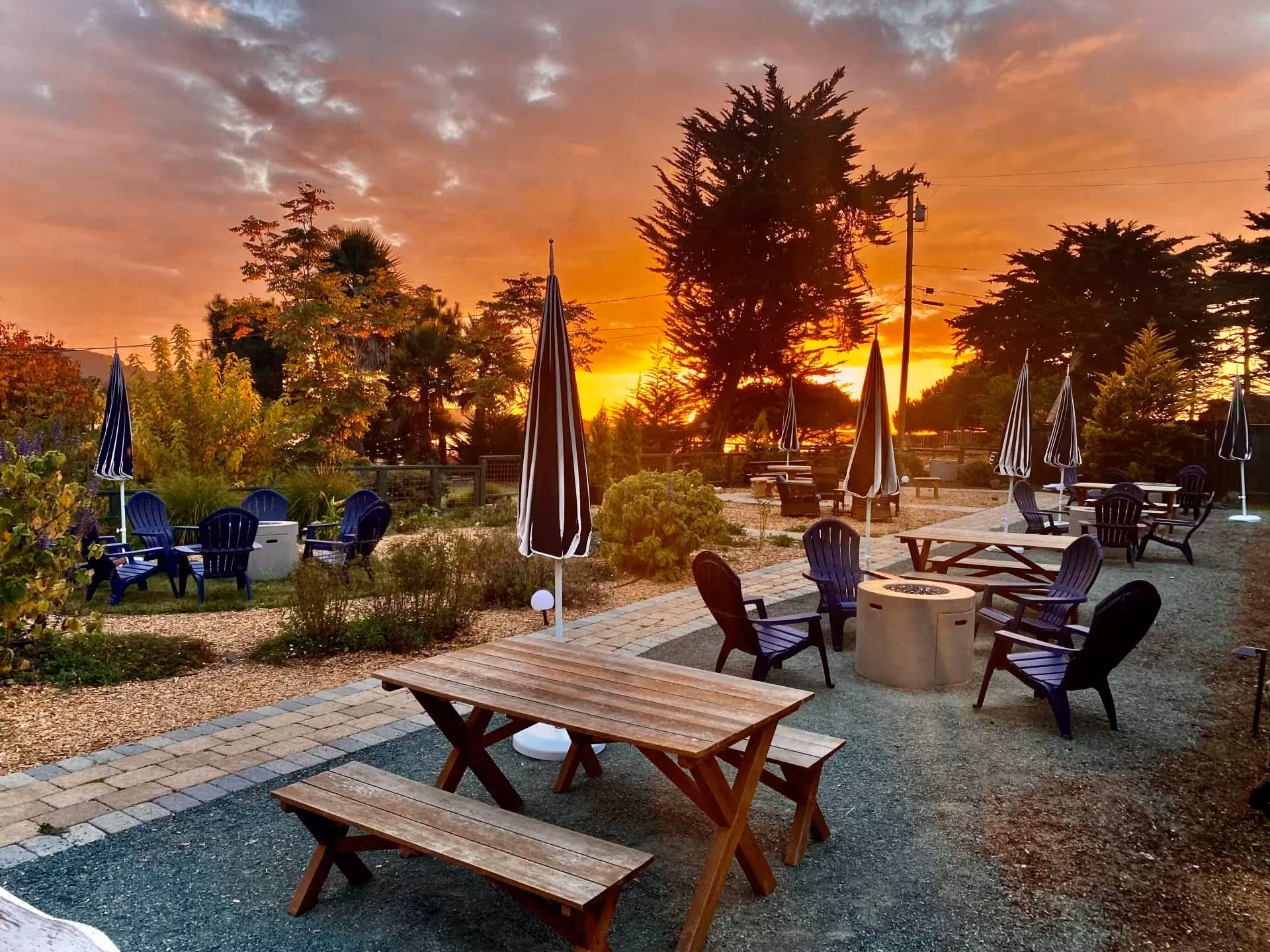 A serene patio with tables and chairs, bathed in warm hues of sunset, creating a tranquil outdoor dining atmosphere.