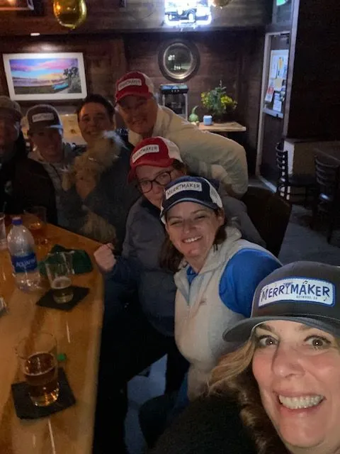 A group of people are sitting around a table with a dog.