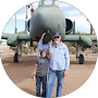 Two people posing together outdoors near a military aircraft at an Arizona air museum or airshow