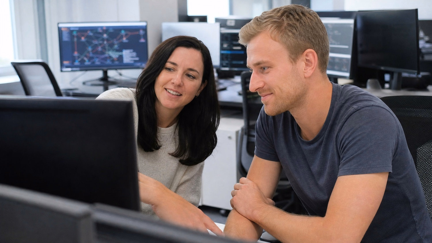 Two IT professionals review network diagram at desks