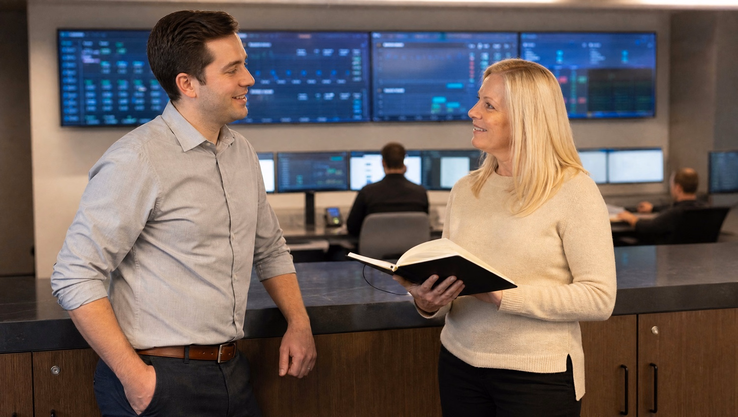 IT staff chat in breakroom, one with notebook