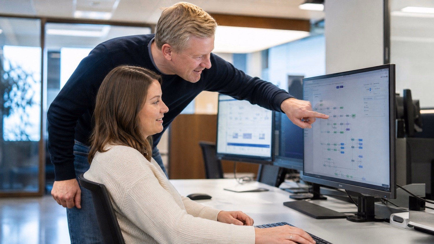 Mentor points at flowchart on womans monitor, workflow analysis 68 chars