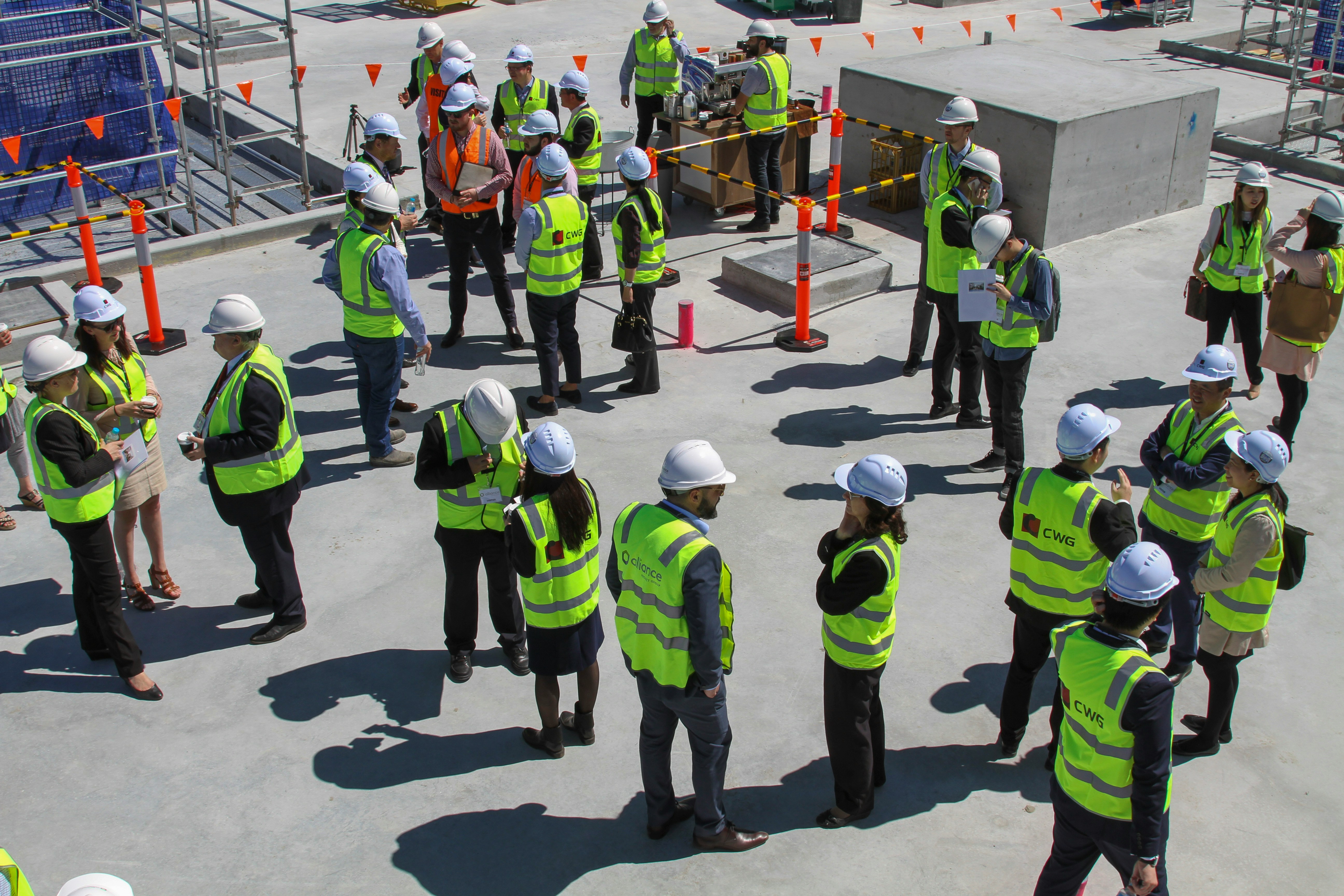 Site workers in hi-vis vests and hard hats gathered for a briefing on a construction site
