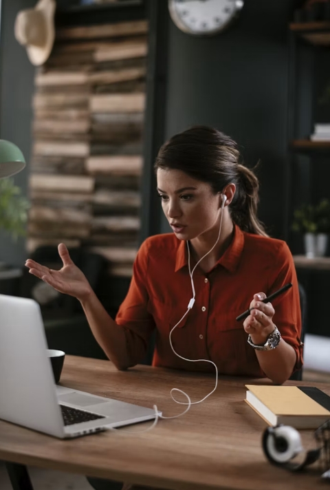 Woman on a video call at her desk, gesturing while speaking into a laptop