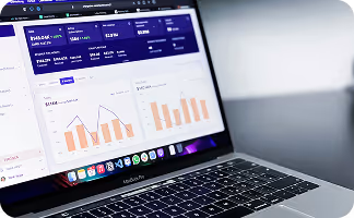 Laptop displaying a data analysis dashboard with graphs on screen, keyboard and dock visible.
