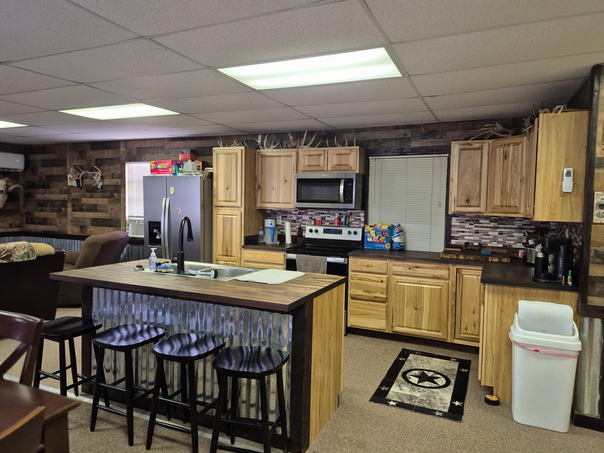 Rustic kitchen with wooden cabinets, a center island with stools, and stainless steel appliances.